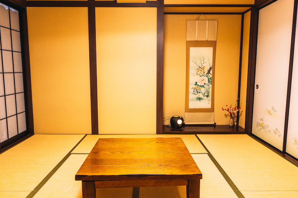 和室の真ん中に木製の机、奥に掛け軸があります